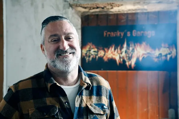 Bild von dem lächelnden Rocker Franky vor seinem Markenhintergrund