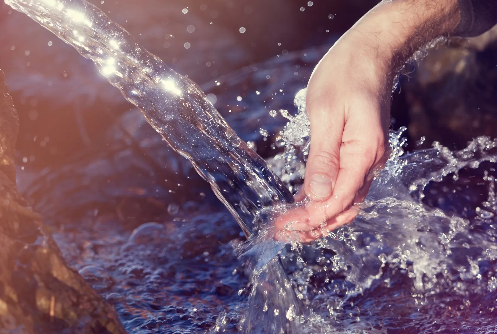 Eine Hand im Quellwasser steht für den sehr hohen Hygienestandard, der für die Industrie gilt