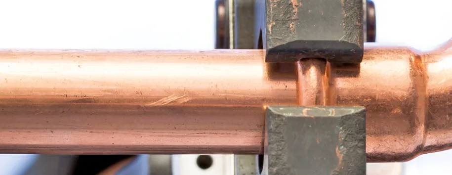 Zugeschnittene Darstellung eines Kupferfittings mit einer Presszange von SANHA®